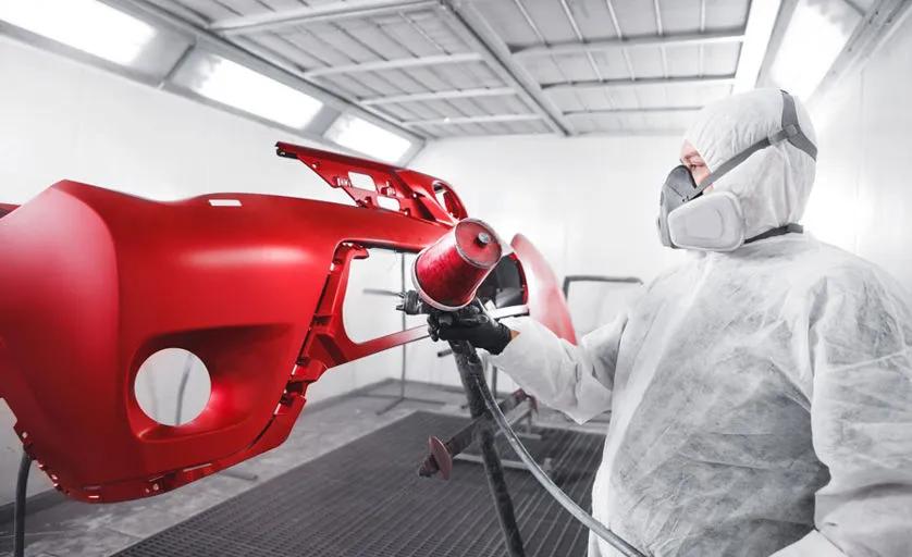 Carrozziere che usa una lucidatrice sulla carrozzeria auto